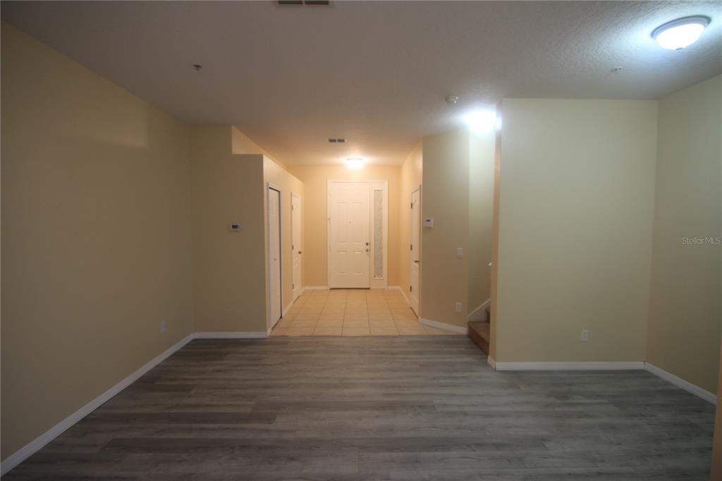 An interior view shows a living area with gray wood-look flooring leading to a tiled entryway — 733 FORTANINI CIRCLE, OCOEE, FL