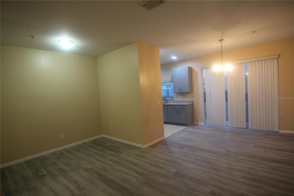 An open-concept dining area with wood-look flooring leads to a kitchen with gray cabinets — 733 FORTANINI CIRCLE, OCOEE, FL