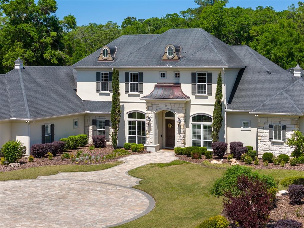A two-story house with a stone facade, dark shutters, and a circular paver driveway — 14742 NW 11TH PLACE, NEWBERRY, FL