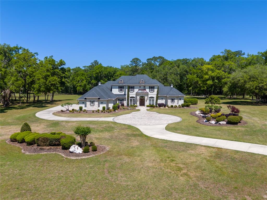 A large two-story house with a circular driveway sits on a grassy, wooded lot — 14742 NW 11TH PLACE, NEWBERRY, FL
