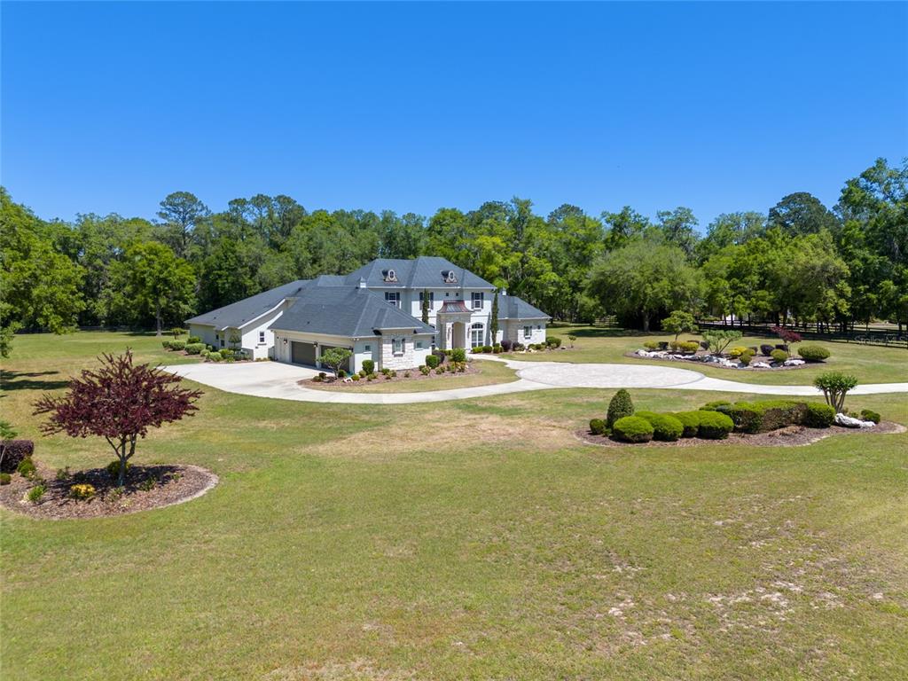 An aerial view of a large, multi-story white house with a dark roof and circular driveway — 14742 NW 11TH PLACE, NEWBERRY, FL