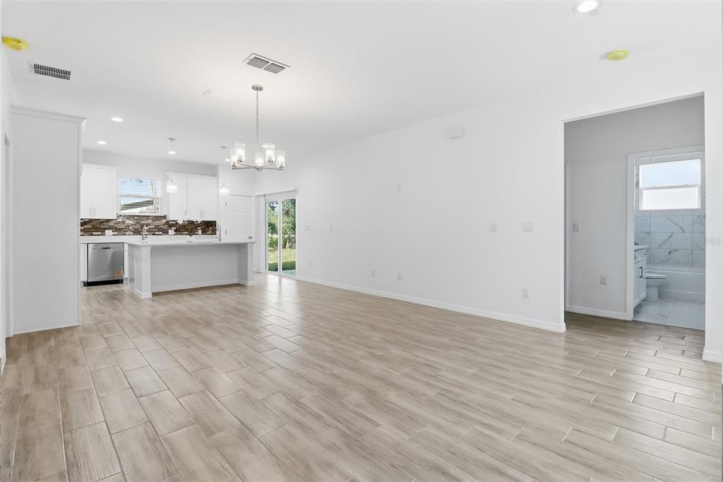 An open-concept living area features light wood-look tile flooring, a kitchen with white cabinetry, and a bathroom — 822 POPLAR STREET, INVERNESS, FL