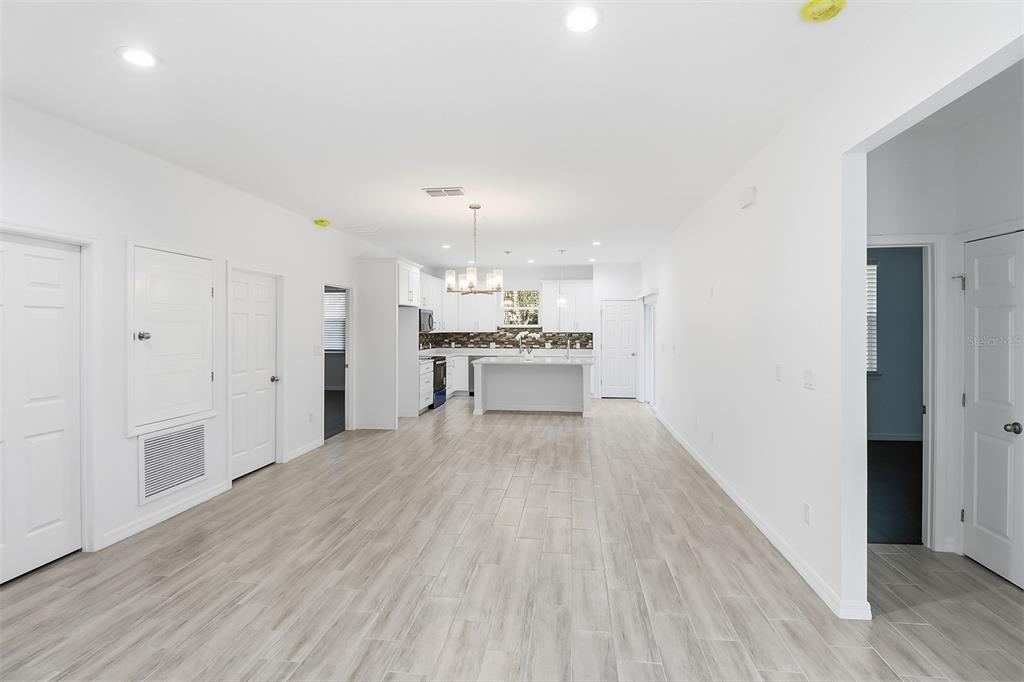 An open-concept living area features light wood-look tile flooring and a kitchen with white cabinetry — 822 POPLAR STREET, INVERNESS, FL