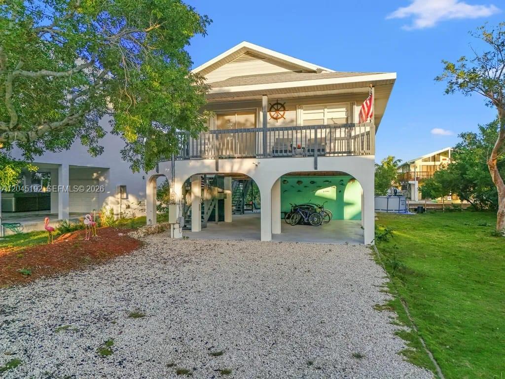 An elevated house with a gravel driveway, a covered ground-level patio, and a wooden balcony — 3635 Trade Winds St, Big Pine FL 33043, BIG PINE, FL
