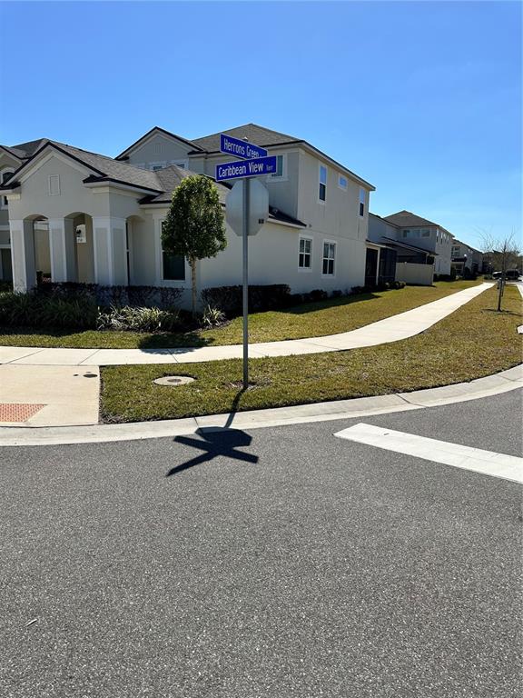 A street sign stands at the corner of a suburban intersection near a two-story house — 1718 CARIBBEAN VIEW TERRACE, KISSIMMEE, FL