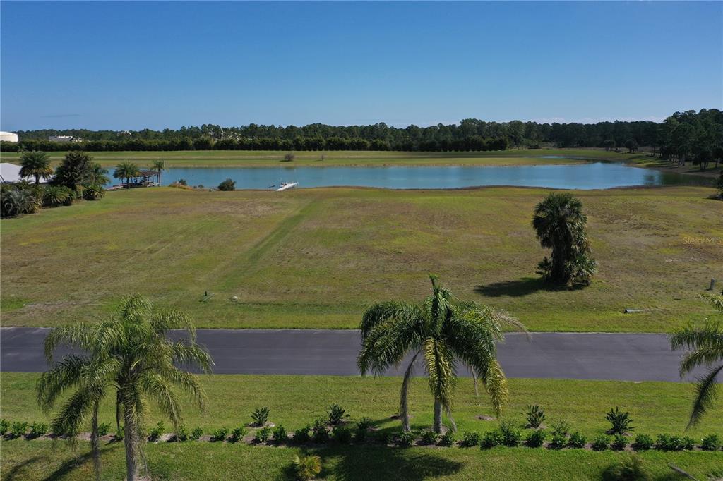 An elevated view of a grassy vacant lot overlooking a lake and distant tree line — 2565 STILLWATER LAKES DRIVE SW, PALM BAY, FL