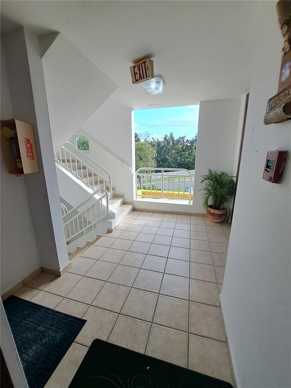 An indoor stairwell landing features tiled floors, a white railing, and an exit sign — A S BUILDING A CORNER S UNIT AC 2, CEIBA, PR