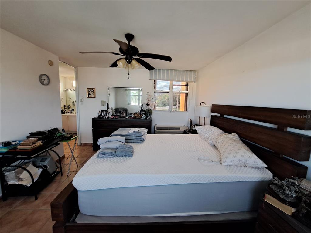 A bedroom features a large bed, a dark wood headboard, and a ceiling fan — A S BUILDING A CORNER S UNIT AC 2, CEIBA, PR
