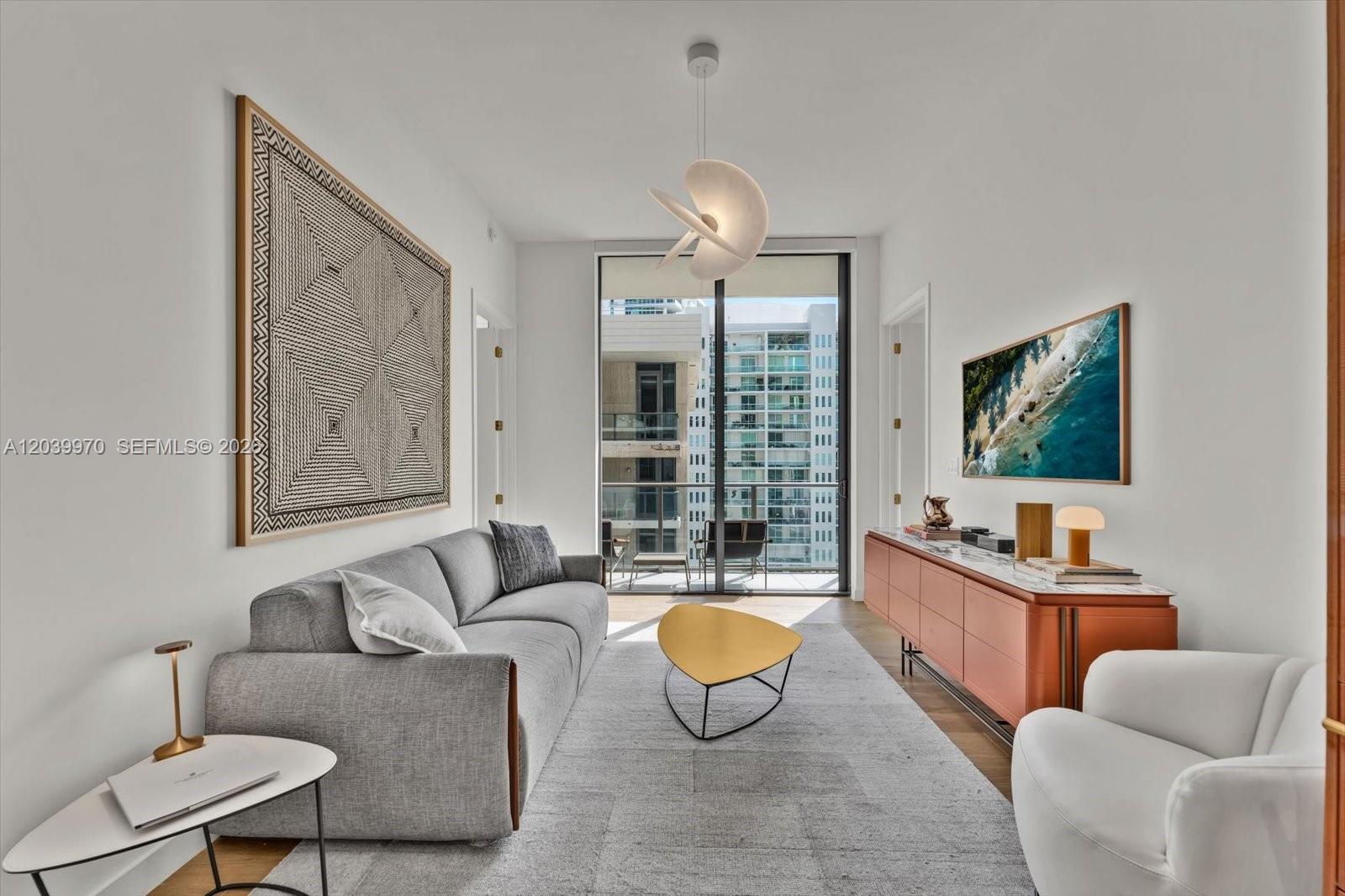 A modern living room features a gray sofa, yellow coffee table, and a balcony view — 2655 S Bayshore Dr # 1206, Miami FL 33133, MIAMI, FL