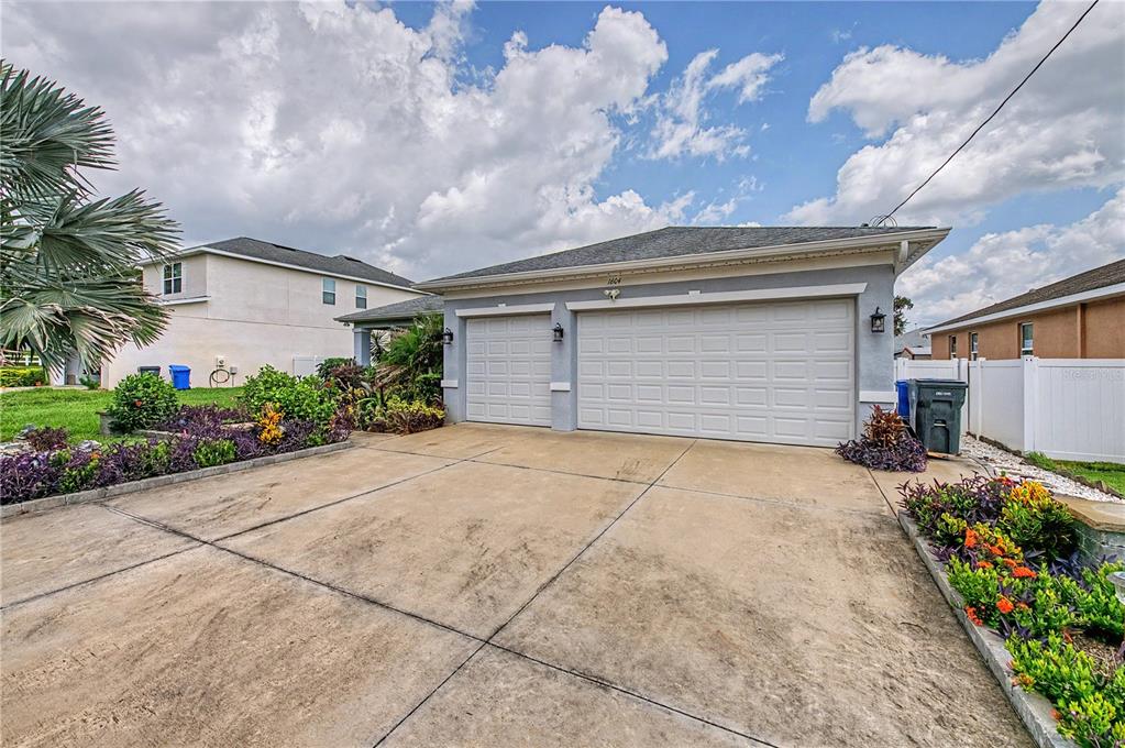 A view of a house exterior featuring a three-car garage and a concrete driveway — 1604 MAIN STREET, VALRICO, FL