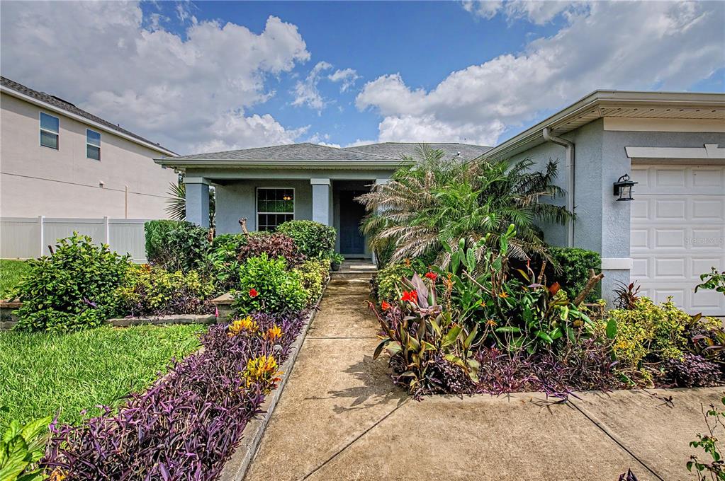 A single-story house with a concrete walkway, landscaped front yard, and an attached garage — 1604 MAIN STREET, VALRICO, FL