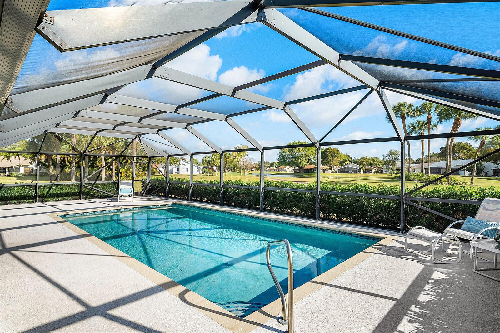 A rectangular swimming pool is enclosed by a screened lanai overlooking a grassy golf course — 5722 Willow Creek Lane, Delray Beach FL 33484, DELRAY BEACH, FL