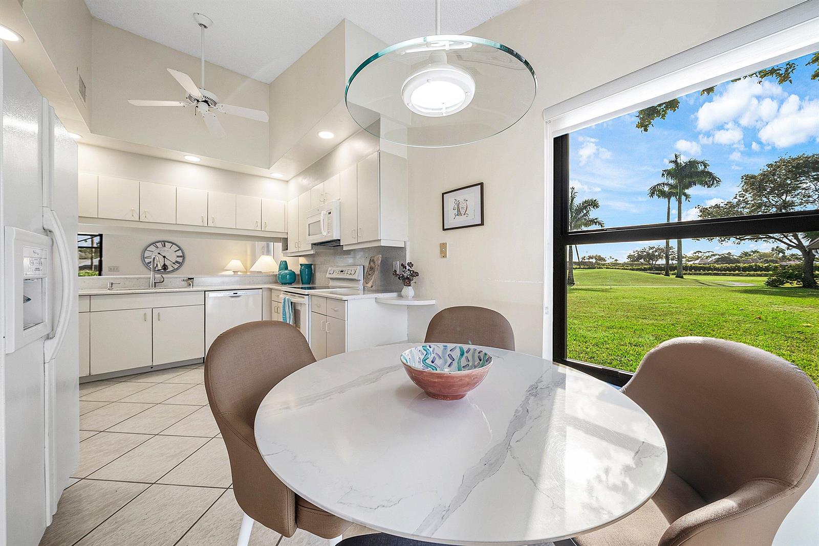 A kitchen and dining area with white cabinets, a marble-top table, and a golf course view — 5722 Willow Creek Lane, Delray Beach FL 33484, DELRAY BEACH, FL