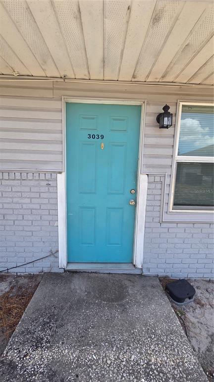 A turquoise front door with the number 3039 is set in a gray brick exterior — 3039 SAINT PAUL DRIVE, WINTER HAVEN, FL