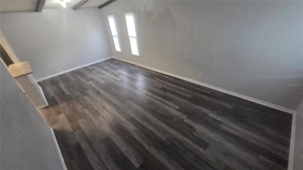 An empty room features gray walls, wood-look plank flooring, and two windows — 3039 SAINT PAUL DRIVE, WINTER HAVEN, FL