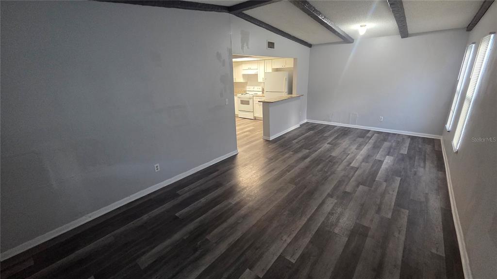 A living room with gray walls, dark wood-look flooring, and a view into the kitchen — 3039 SAINT PAUL DRIVE, WINTER HAVEN, FL