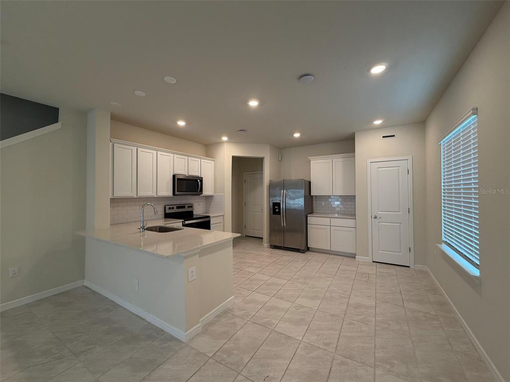 A kitchen features white cabinets, stainless steel appliances, a breakfast bar, and light tile flooring — 2803 STUNNING AVENUE, DAVENPORT, FL