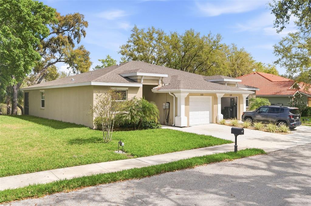 A single-story tan stucco house with a two-car garage and a front lawn — 132 51ST STREET CIRCLE E, PALMETTO, FL