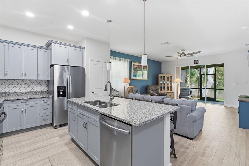 A kitchen with light blue cabinets and granite countertops opens into a living room area — 132 51ST STREET CIRCLE E, PALMETTO, FL