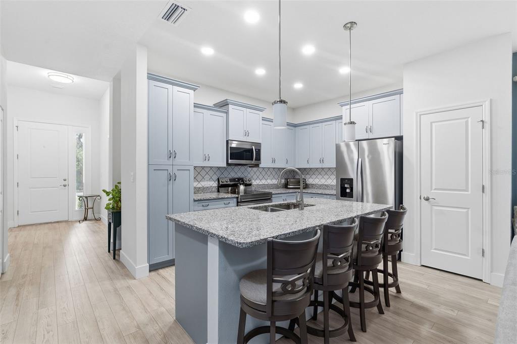 A kitchen with light blue cabinets, granite countertops, a center island, and stainless steel appliances — 132 51ST STREET CIRCLE E, PALMETTO, FL