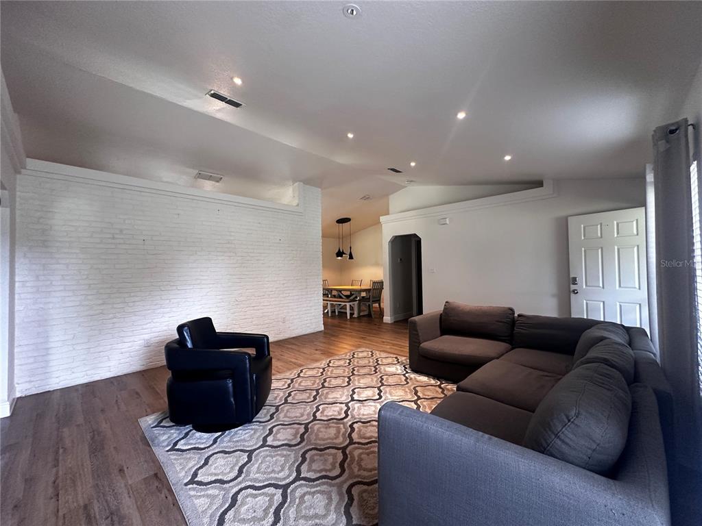 A living room features a white brick wall, a gray sectional, and a black chair — 11988 SW 38TH STREET, OCALA, FL