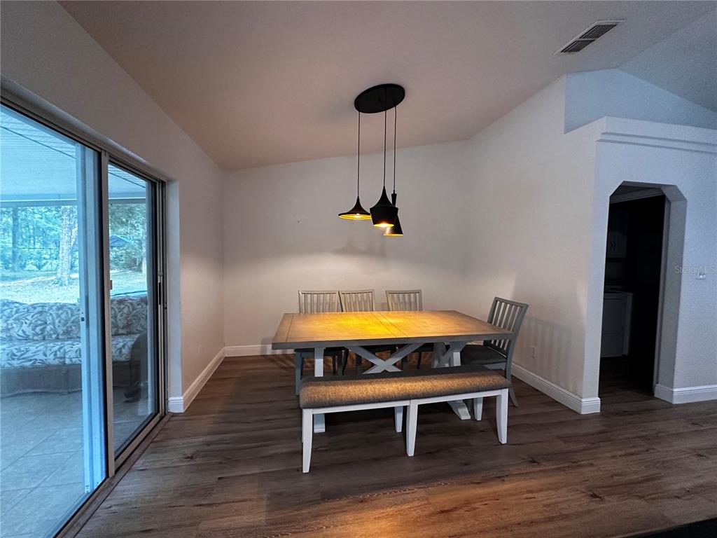 A dining area features a wooden table, chairs, a bench, and pendant lighting — 11988 SW 38TH STREET, OCALA, FL