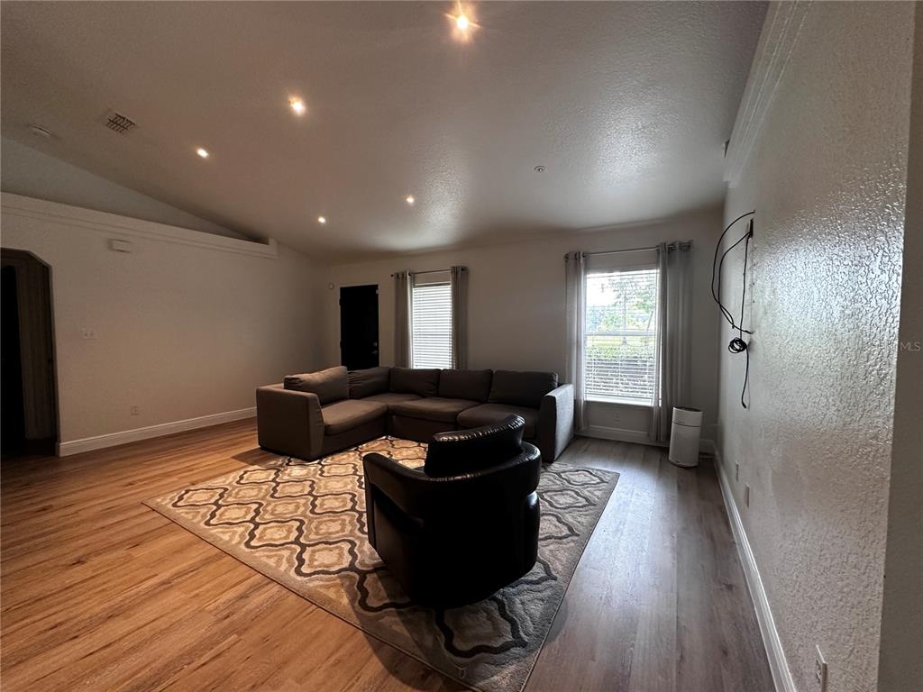 A living room features a gray sectional sofa, a black armchair, and wood-look flooring — 11988 SW 38TH STREET, OCALA, FL