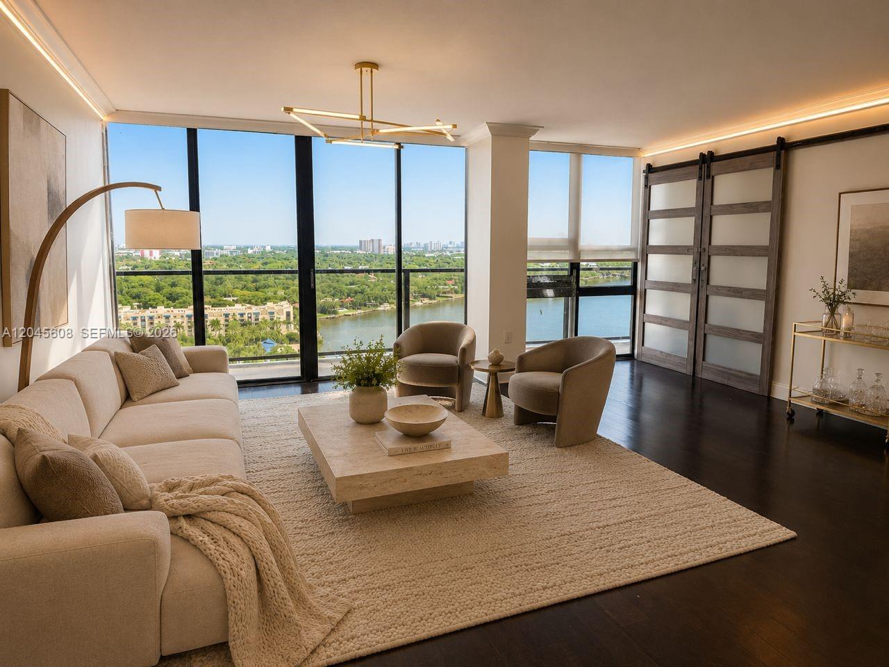 A modern living room features a beige sofa, two armchairs, and floor-to-ceiling windows overlooking water — 600 NE 36 St, Miami FL 33137, MIAMI, FL