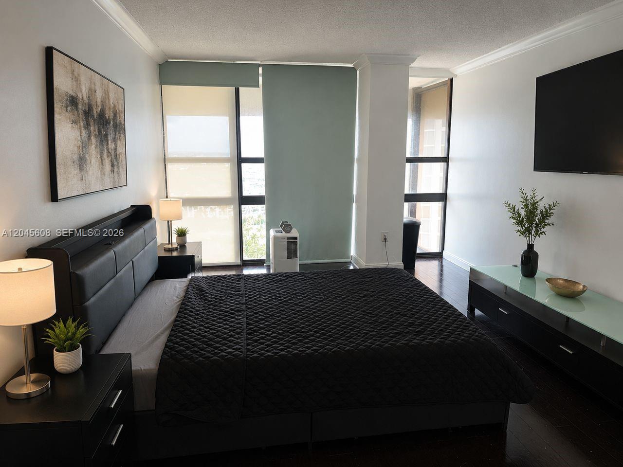 A bedroom features a black bed, dark wood floors, and floor-to-ceiling windows with light-colored shades — 600 NE 36 St, Miami FL 33137, MIAMI, FL