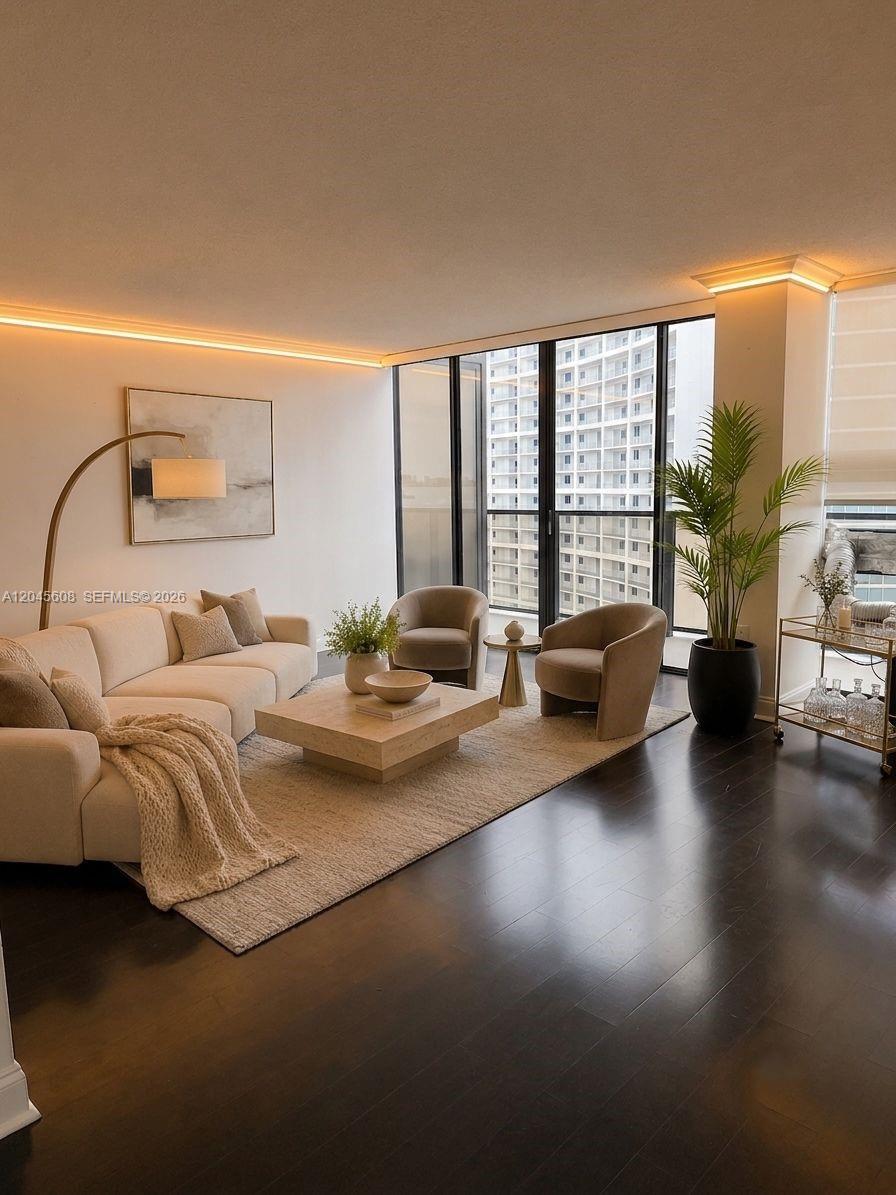 A modern living room features a beige sofa, two armchairs, a coffee table, and floor-to-ceiling windows — 600 NE 36 St, Miami FL 33137, MIAMI, FL