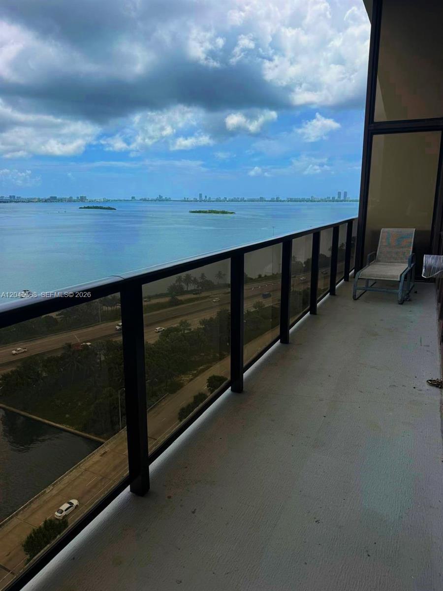 A balcony with a glass railing overlooks a highway and a large body of water — 600 NE 36 St, Miami FL 33137, MIAMI, FL