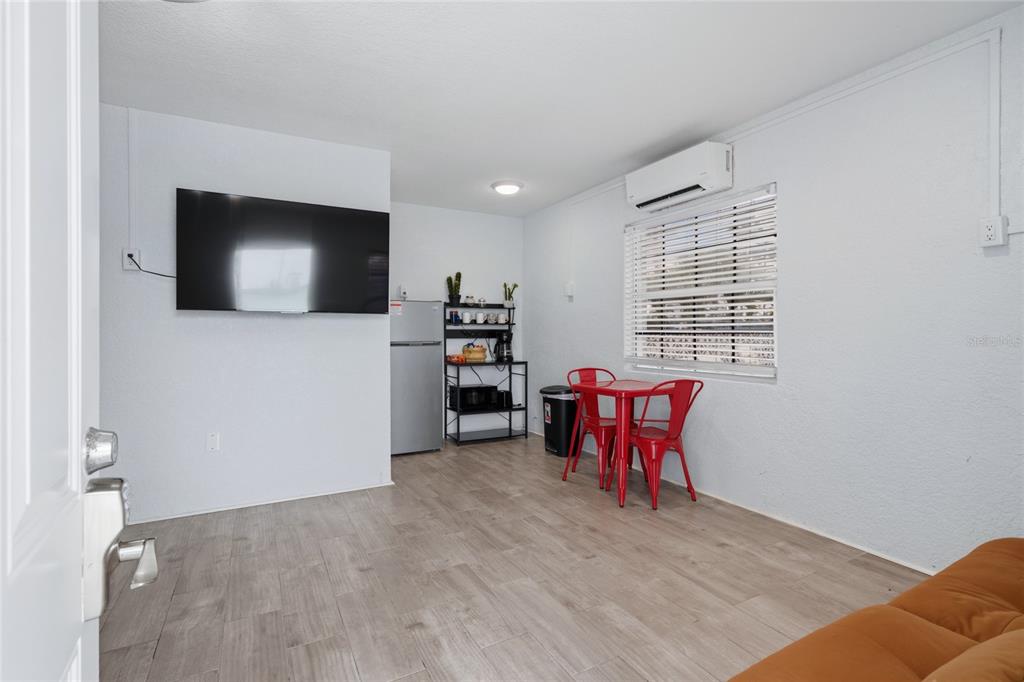 A small room features light wood-look flooring, a wall-mounted television, and a red dining set — 602 POINSETTIA AVENUE, CLEARWATER BEACH, FL