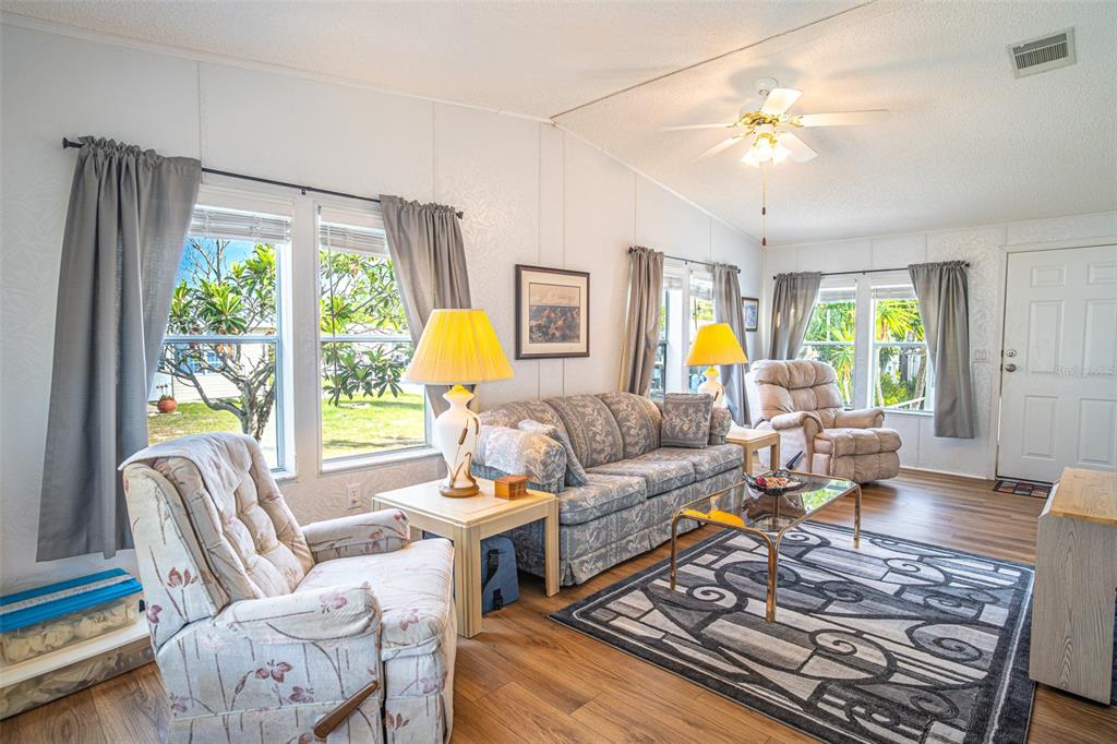 A living room features a sofa, two armchairs, a coffee table, and wood-look flooring — 56 BEAVERKILL DRIVE, LAKE WALES, FL