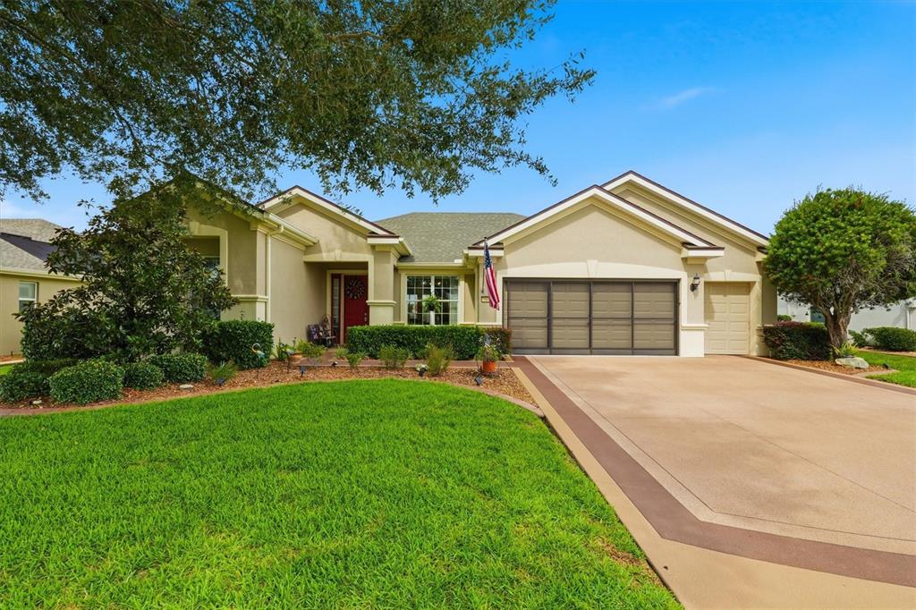 A tan house exterior features a red front door, a walkway, and a green hedge — 6865 SW 97TH TERRACE ROAD, OCALA, FL