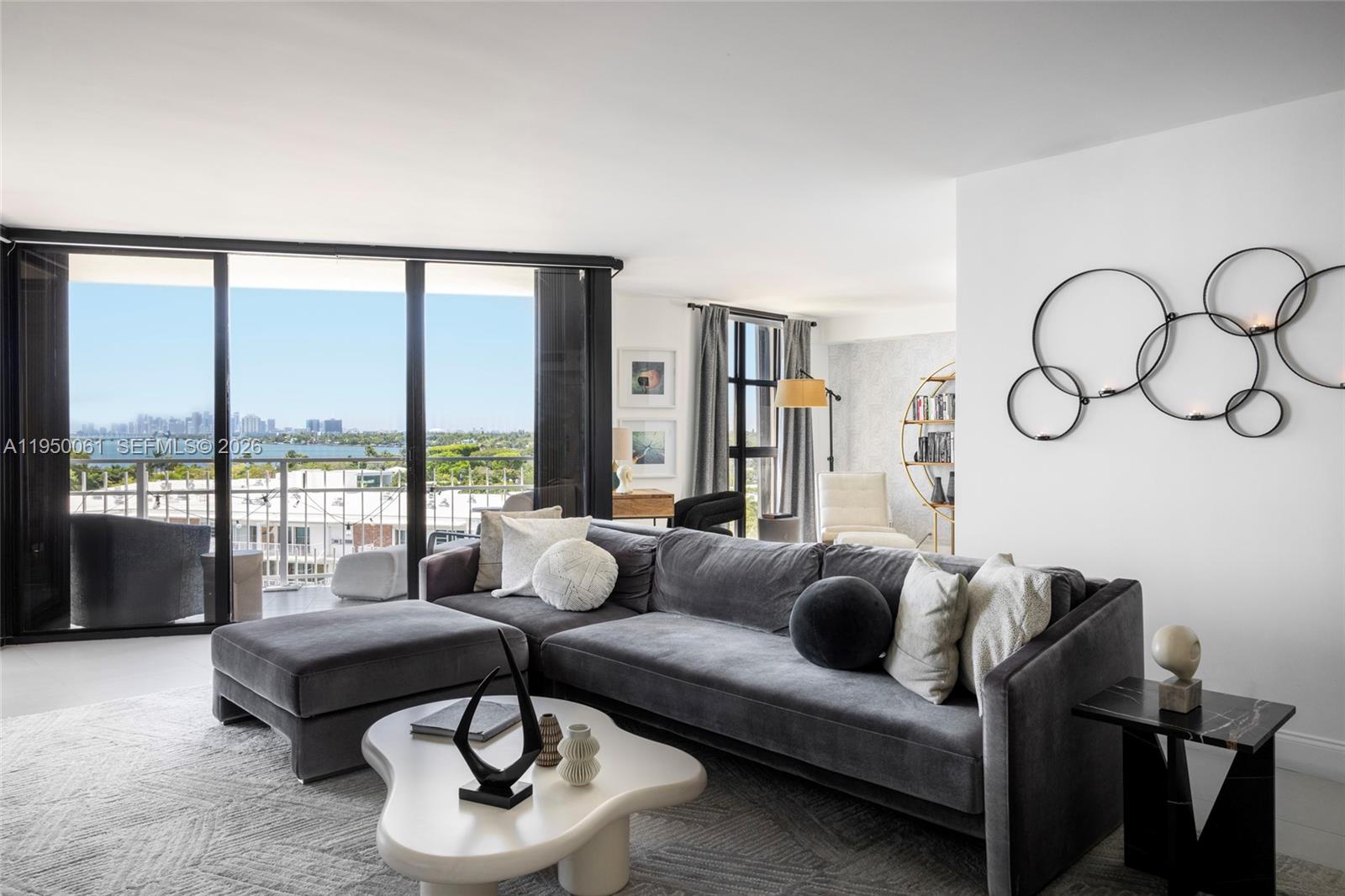 A modern living room features a grey sectional sofa, a white organic coffee table, and balcony views — 4000 Towerside Ter # 804, Miami FL 33138, MIAMI, FL