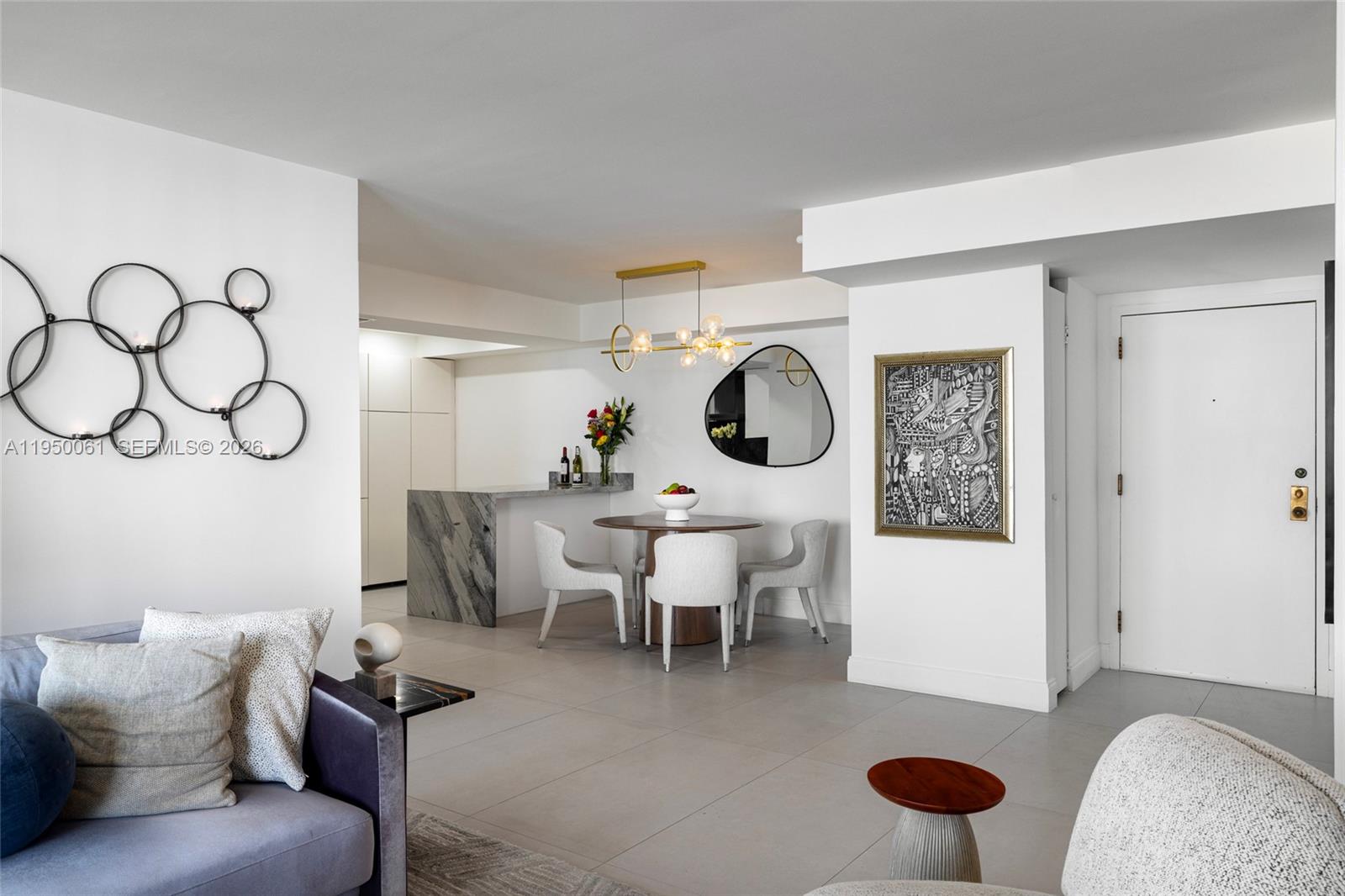 A modern dining area features a round table, white chairs, and a marble breakfast bar — 4000 Towerside Ter # 804, Miami FL 33138, MIAMI, FL