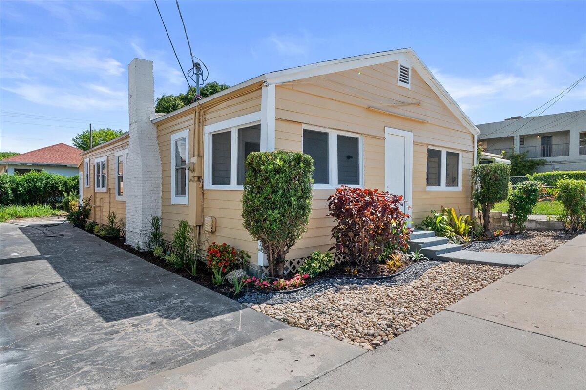 A single-story yellow house with a white chimney and a paved driveway — 1011 22nd Street, West Palm Beach FL 33407, WEST PALM BEACH, FL