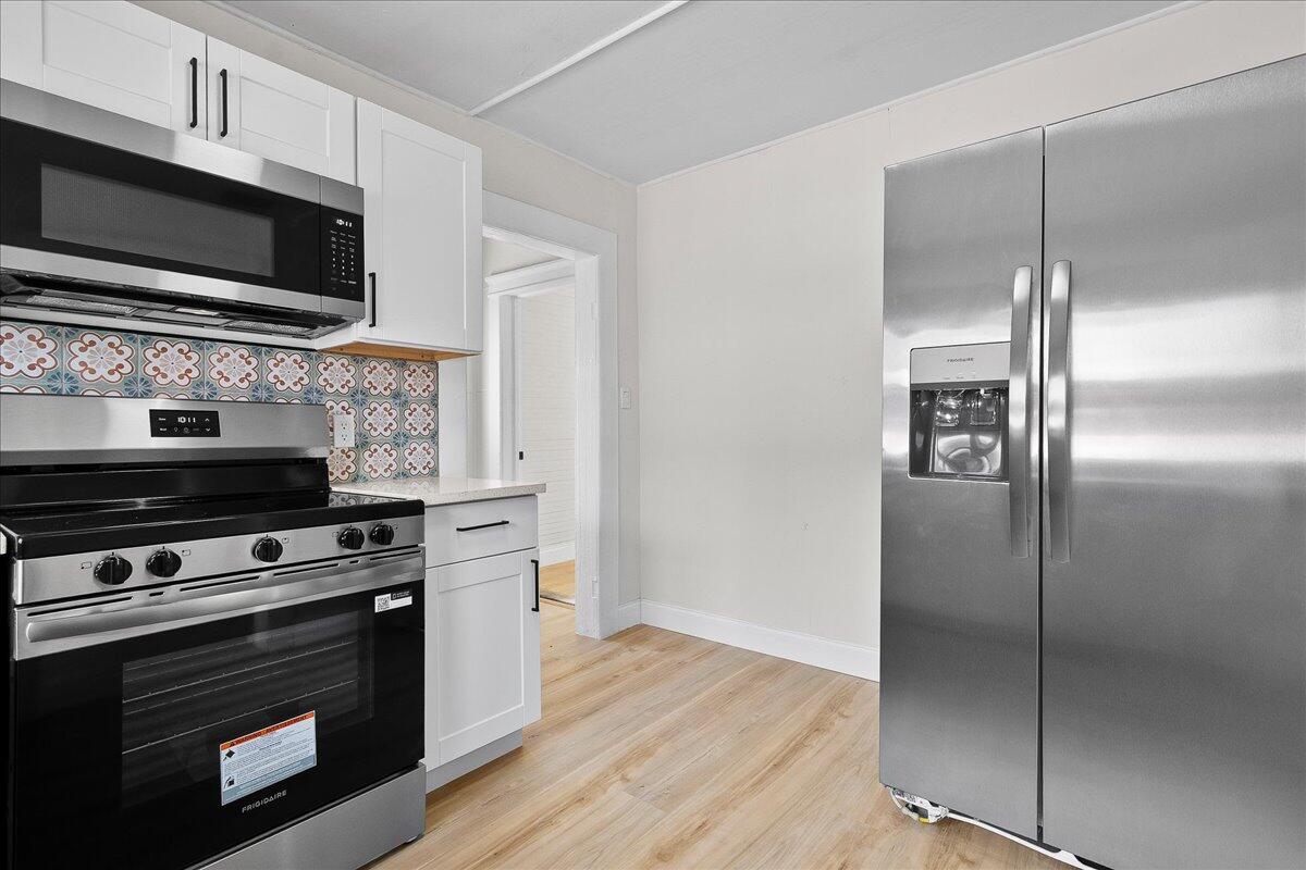 A kitchen features white cabinets, stainless steel appliances, and a patterned tile backsplash — 1011 22nd Street, West Palm Beach FL 33407, WEST PALM BEACH, FL