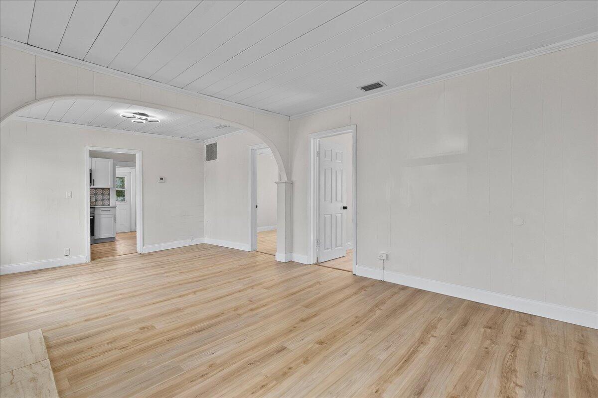 An empty room with light wood-look flooring, white walls, and a large arched entryway — 1011 22nd Street, West Palm Beach FL 33407, WEST PALM BEACH, FL