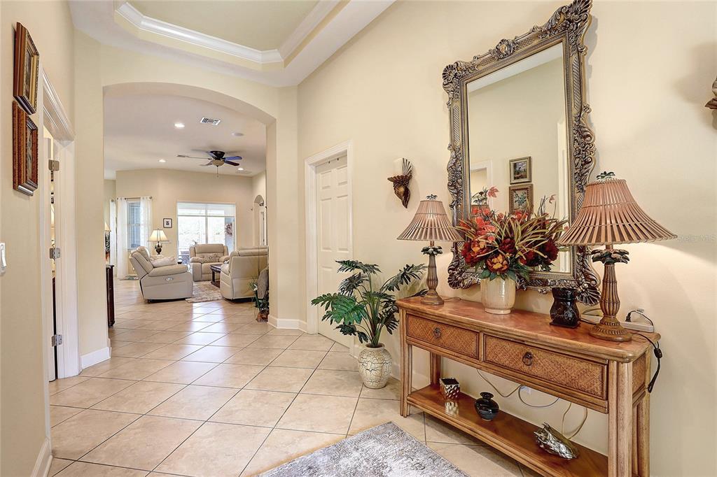 A tiled foyer features a console table with lamps, a large mirror, and an arched entryway — 2542 CORTENOVA COURT, VENICE, FL
