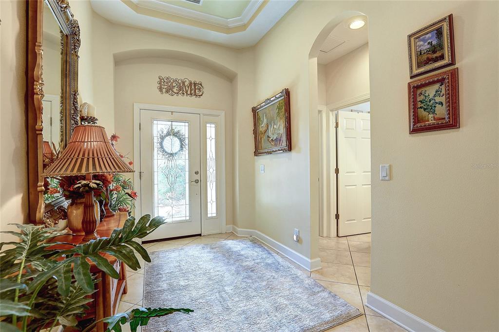 A foyer features tile flooring, a decorative rug, a front door with sidelights, and wall art — 2542 CORTENOVA COURT, VENICE, FL