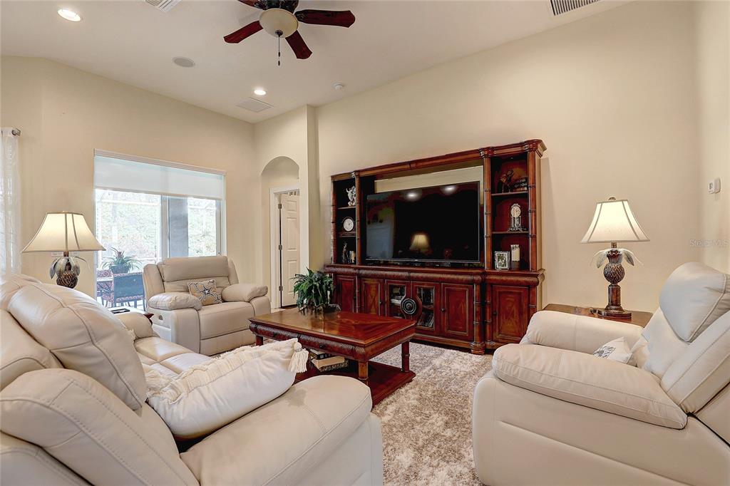 A living room features light-colored leather furniture, a large wooden entertainment center, and a coffee table — 2542 CORTENOVA COURT, VENICE, FL