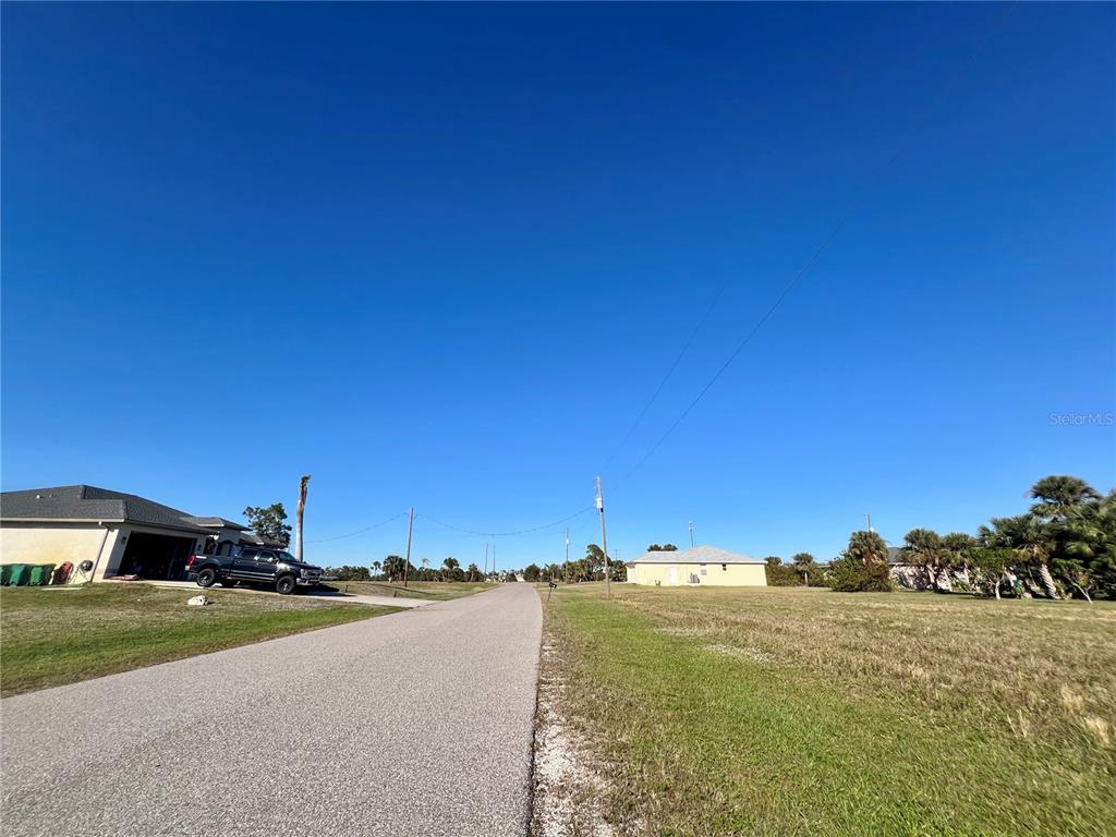 A paved road runs between a residential house and an empty grassy lot — 17 BRIG CIRCLE E, PLACIDA, FL