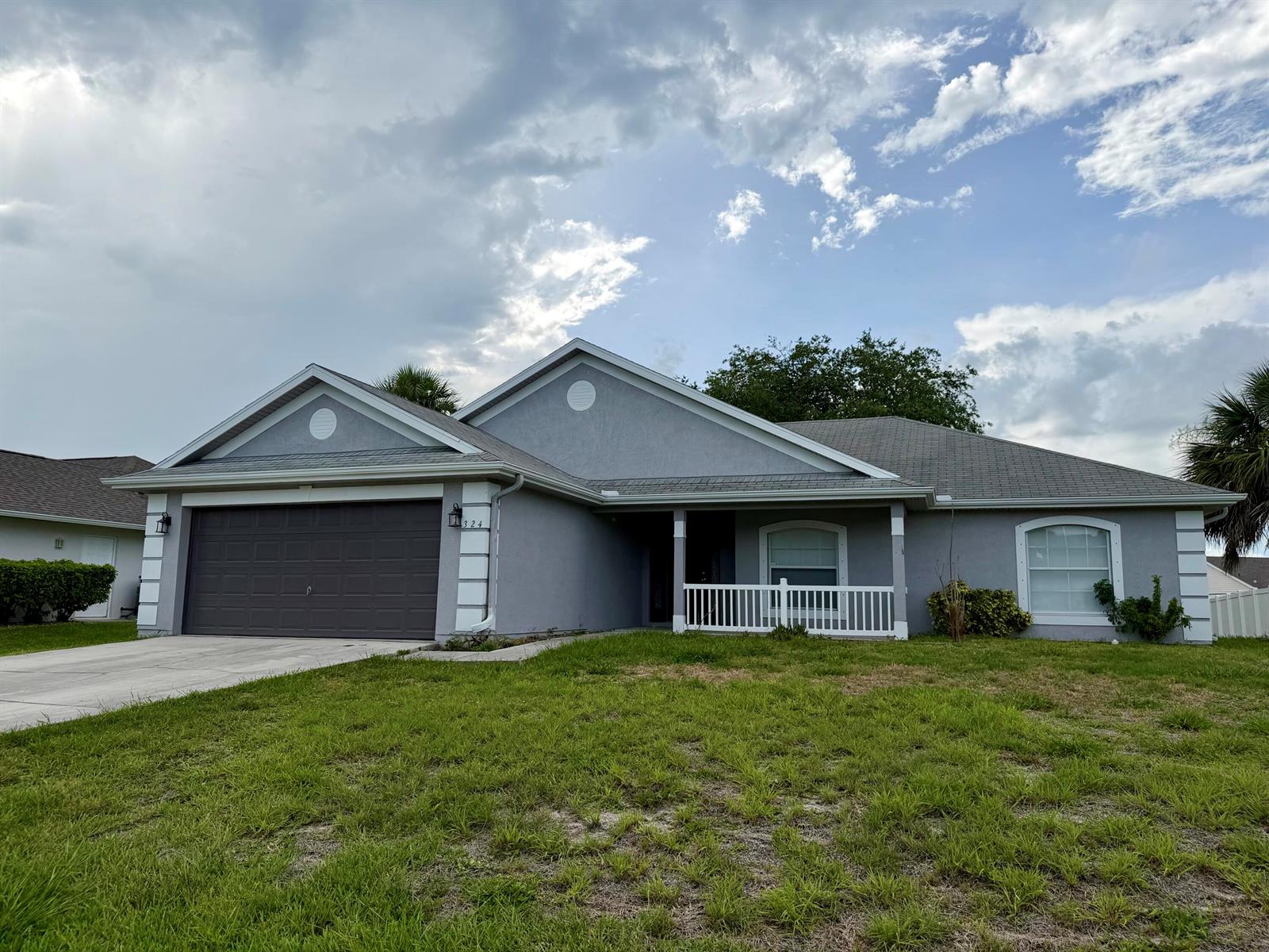 A single-story gray house features a two-car garage, a white-railed front porch, and arched windows — 324 Seaside Terrace, Sebastian FL 32958, SEBASTIAN, FL
