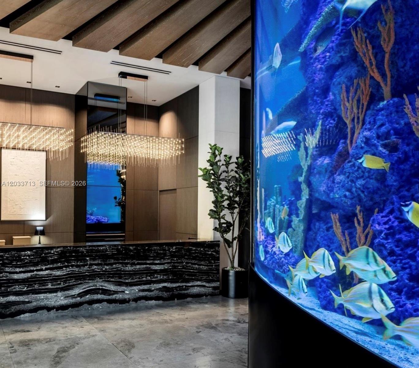 A modern lobby features a large curved aquarium, a black stone desk, and crystal chandeliers — 1451 Brickell Ave # 2701, Miami FL 33131, MIAMI, FL