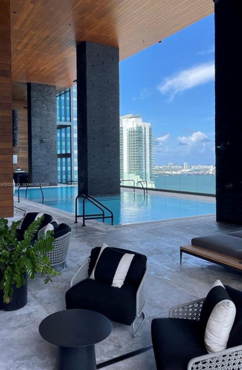 A covered outdoor lounge area features a swimming pool overlooking a city skyline and water — 1451 Brickell Ave # 2701, Miami FL 33131, MIAMI, FL