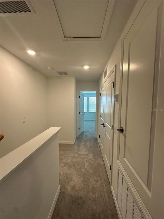 A carpeted hallway features white walls, recessed lighting, and several closed interior doors — 3137 SKYLINE LOOP, KISSIMMEE, FL