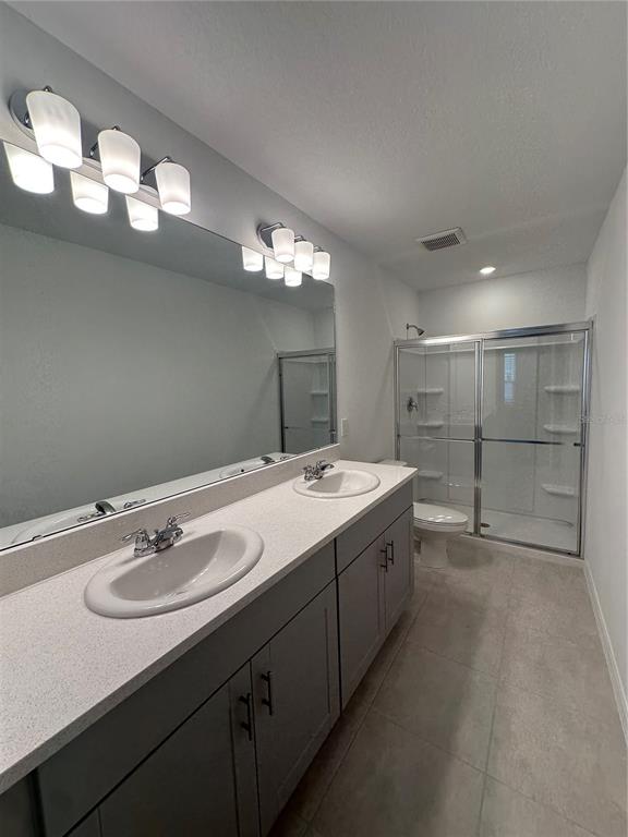 A bathroom features a double vanity with gray cabinets, a large mirror, and a glass shower — 3137 SKYLINE LOOP, KISSIMMEE, FL