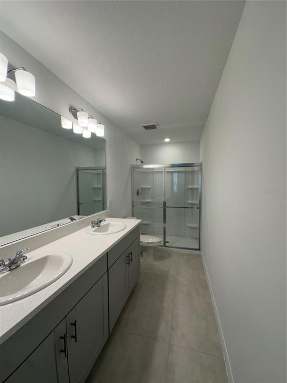 A bathroom features a double vanity with gray cabinets, a large mirror, and a glass shower — 3137 SKYLINE LOOP, KISSIMMEE, FL