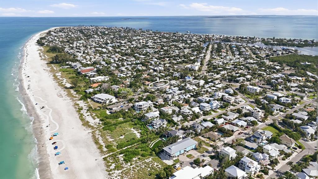 An aerial view shows a coastal neighborhood with a sandy beach and many houses — 115 AQUA LANE, HOLMES BEACH, FL